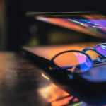 Notebook com óculos de grau apoiado